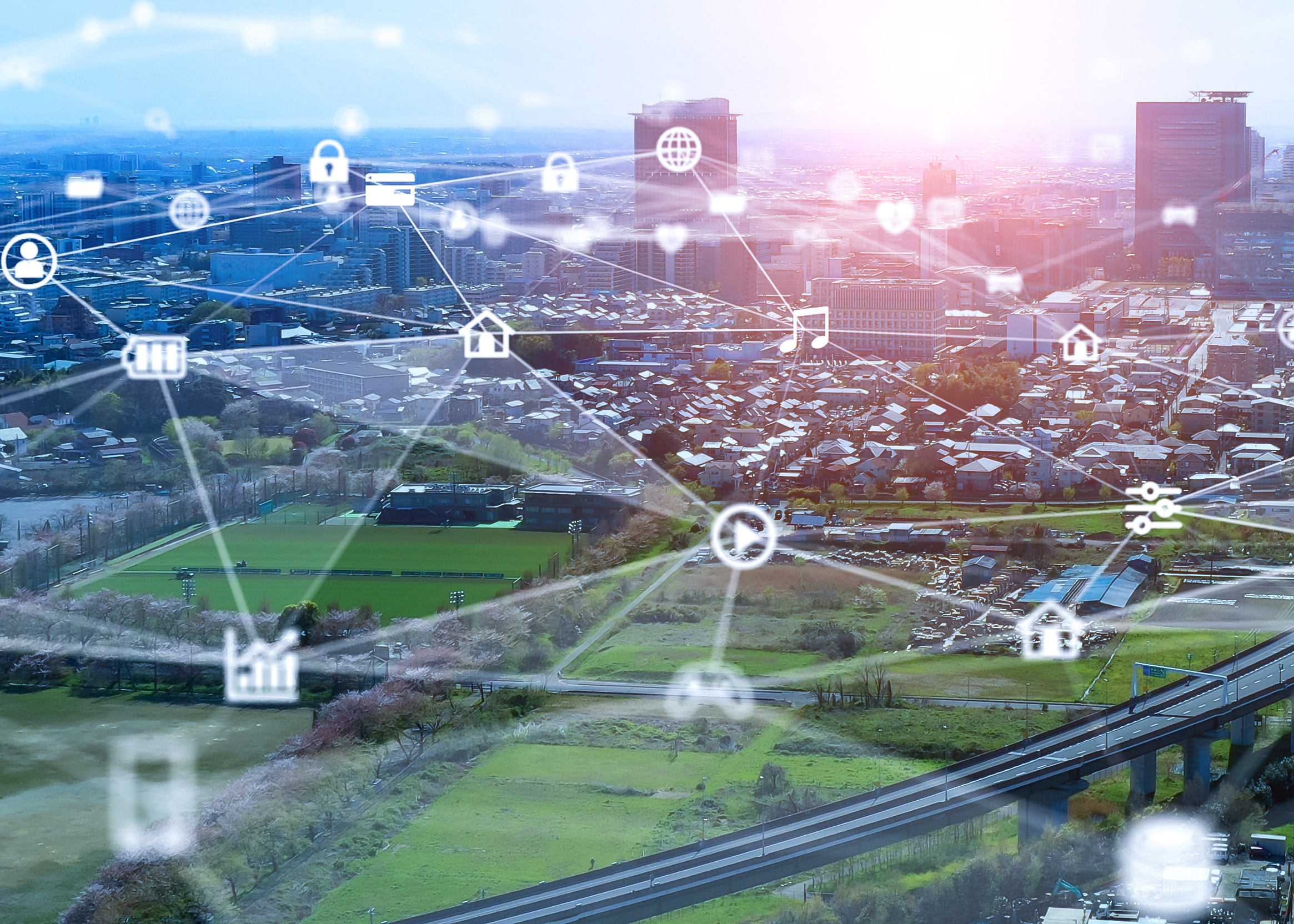 A city in distance and green space in foreground overlaid with graphics suggesting a broadband network