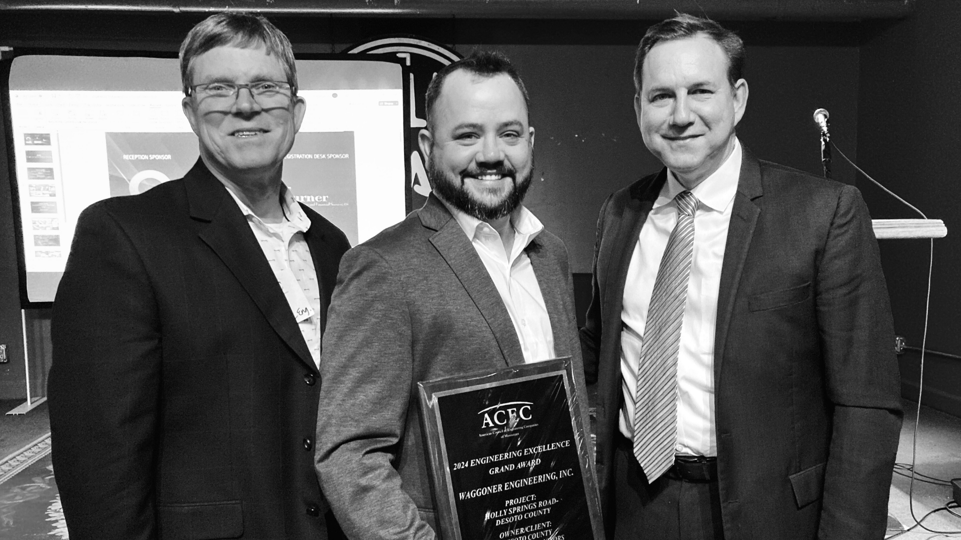 Waggoner - ACEC-MS Grand Award Holly Springs Road Hunter Arnold, Jason Youngblood, and Tracy Huffman pose with an ACEC Engineering Excellence Grand Award plaque for the Holly Springs Road project.