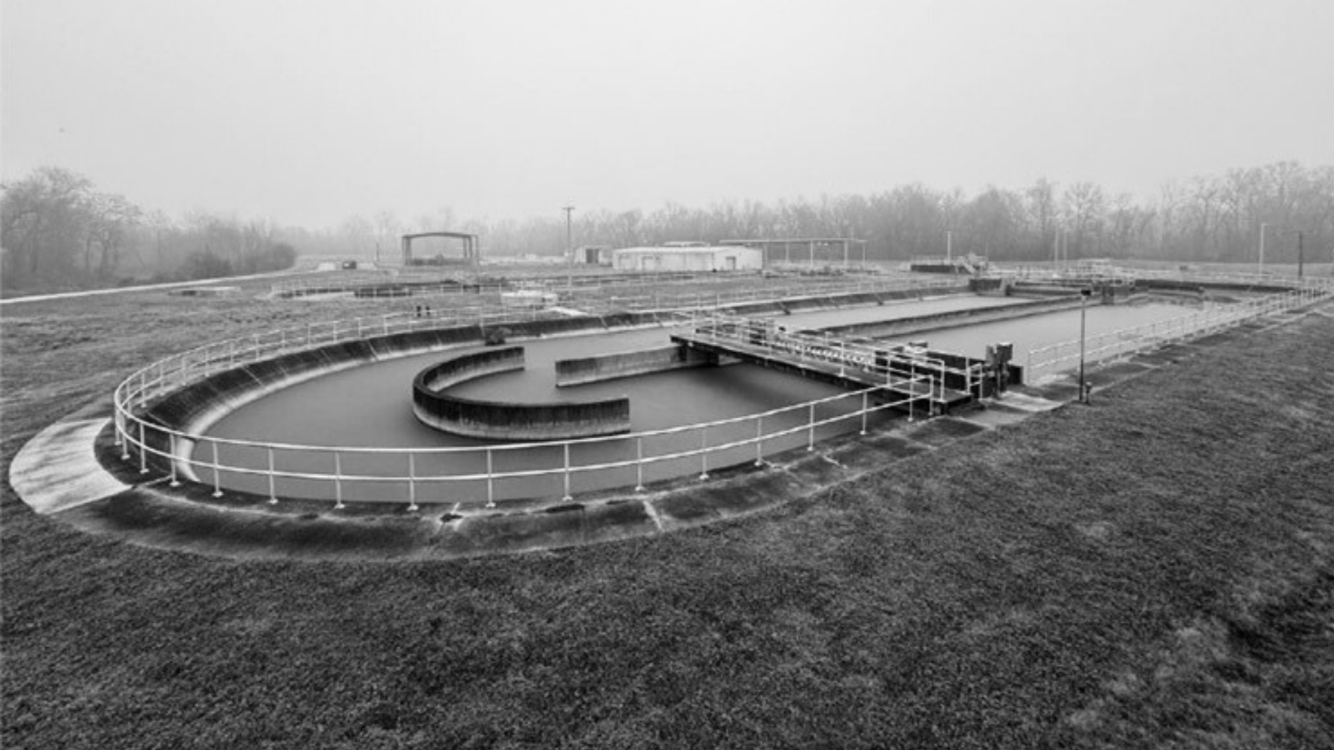 Waggoner - City of Bossier City Public Private Partnership Black-and-white photo of a wastewater treatment facility in Bossier City, showing circular clarifier basins and surrounding infrastructure as part of a public-private partnership project.